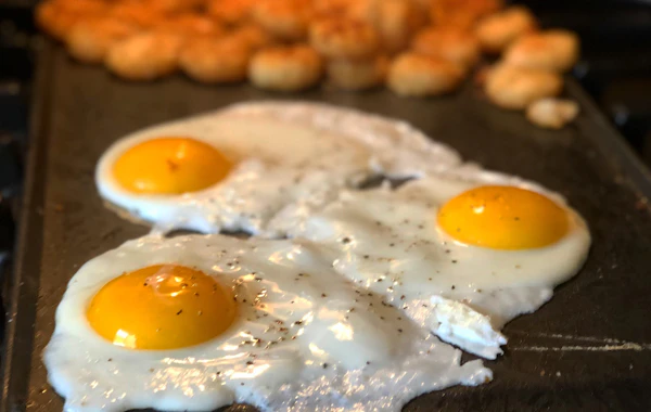 Fried eggs cooking on a flat griddle