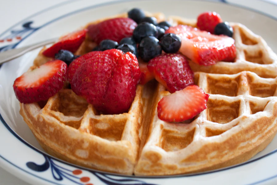 Waffle topped with strawberries and blueberries